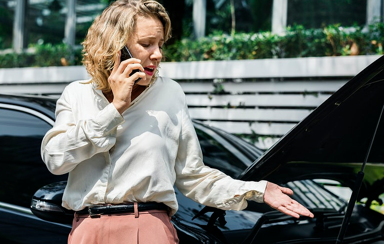 woman talking on the phone with broken car